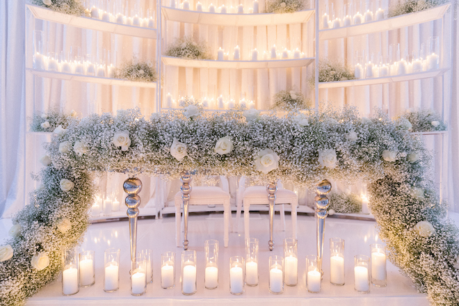 A table decorated with baby's breath, white roses and candles.