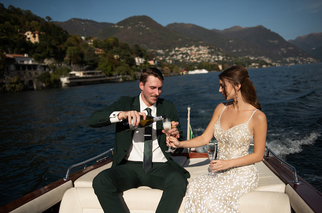 The groom pouring a glass of champagne for the bride on the boat. 