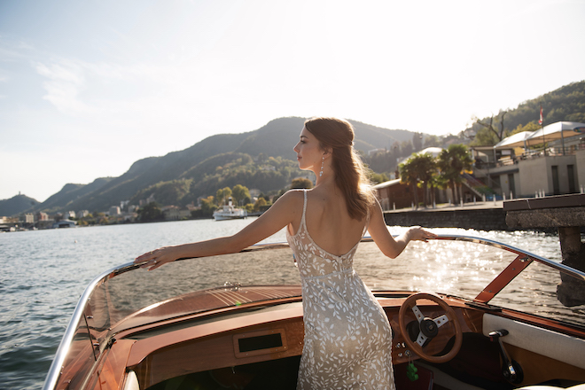 The bride standing at the front of a boat looking to the side.