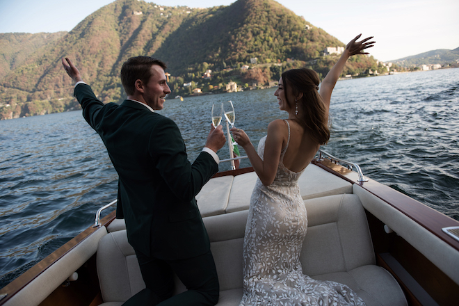 The bride and groom clinking glasses and looking at each other for their waterfront elopement in Lake Como, Italy.