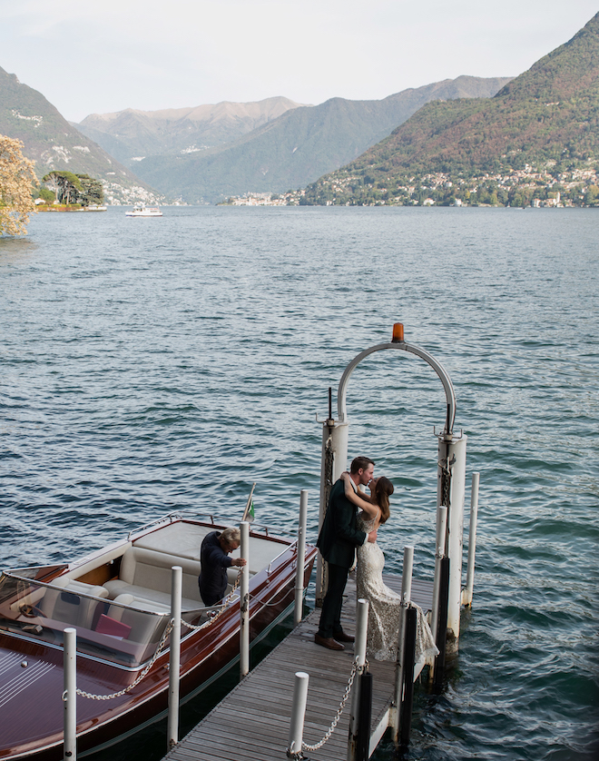 The bride and groom kissing on a dock next to a boat for their elopement in Lake Como, Italy.