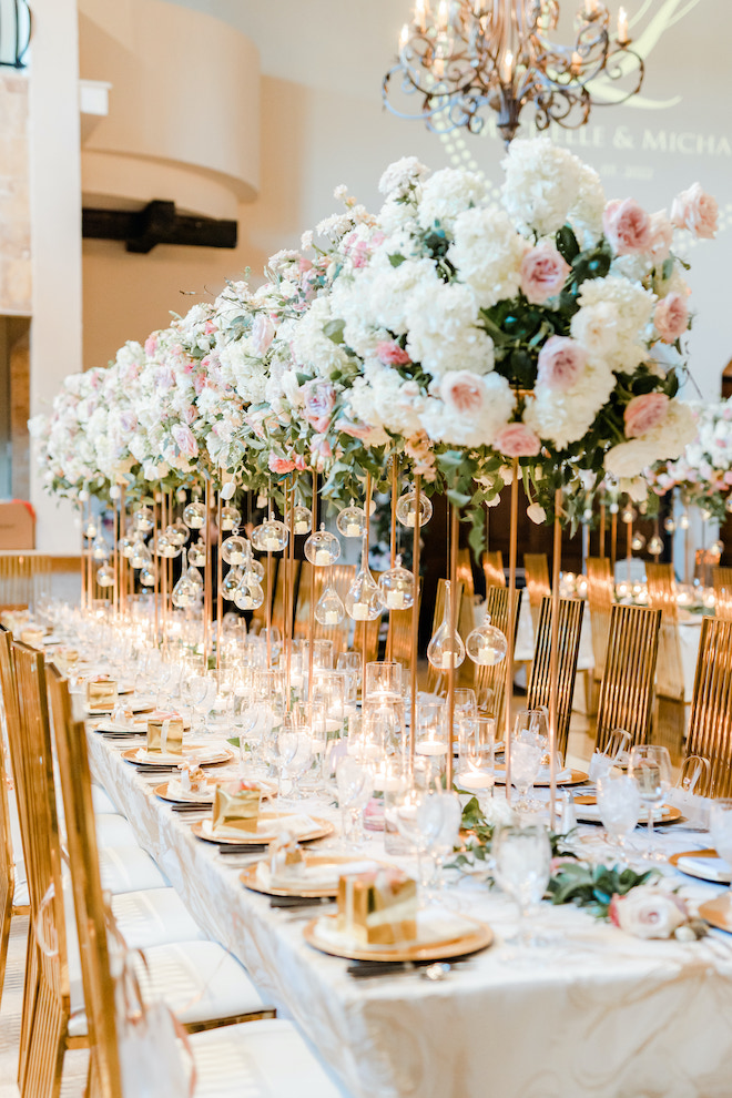 The reception table filled with pink hued florals and gold decor