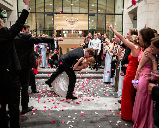 The bride and groom kissing during their rose petal send off.