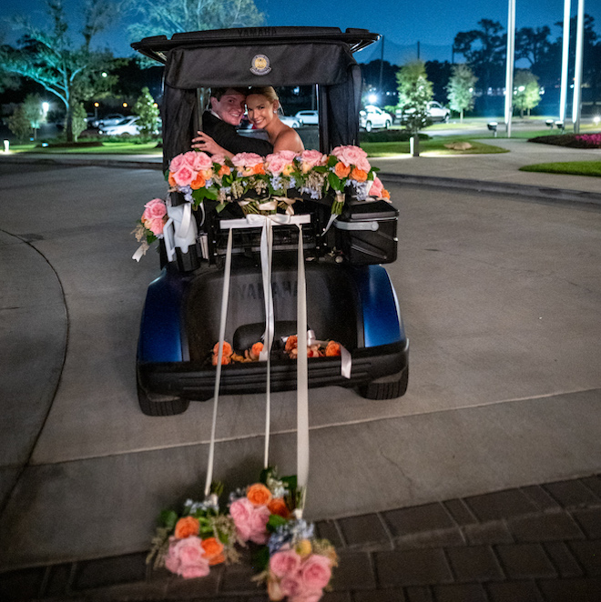 The bride and groom leaving their elegant spring wedding on a golf cart decorated in florals.