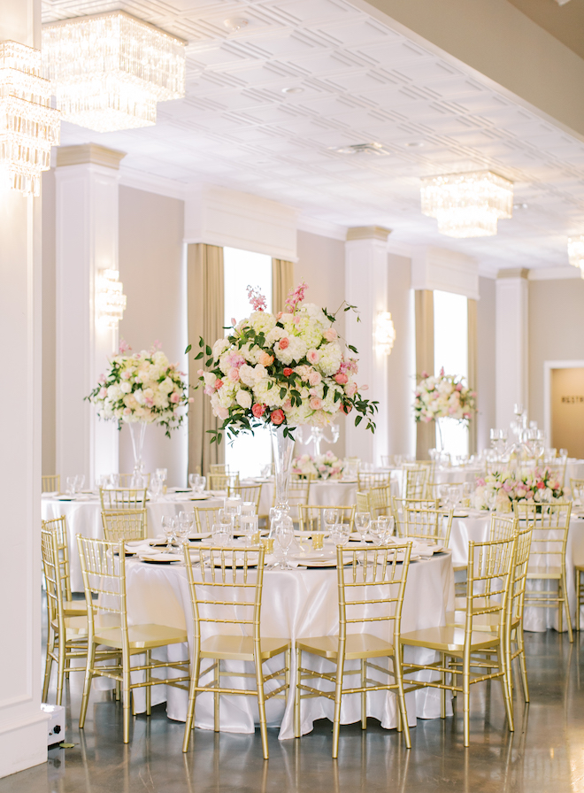 Round white reception tables with gold chairs and light and bright floral centerpieces of pink and ivory florals.