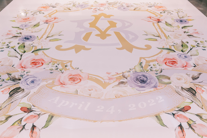 A custom dance floor with the couple's initials and the date April, 24, 2022, with pastel florals. 