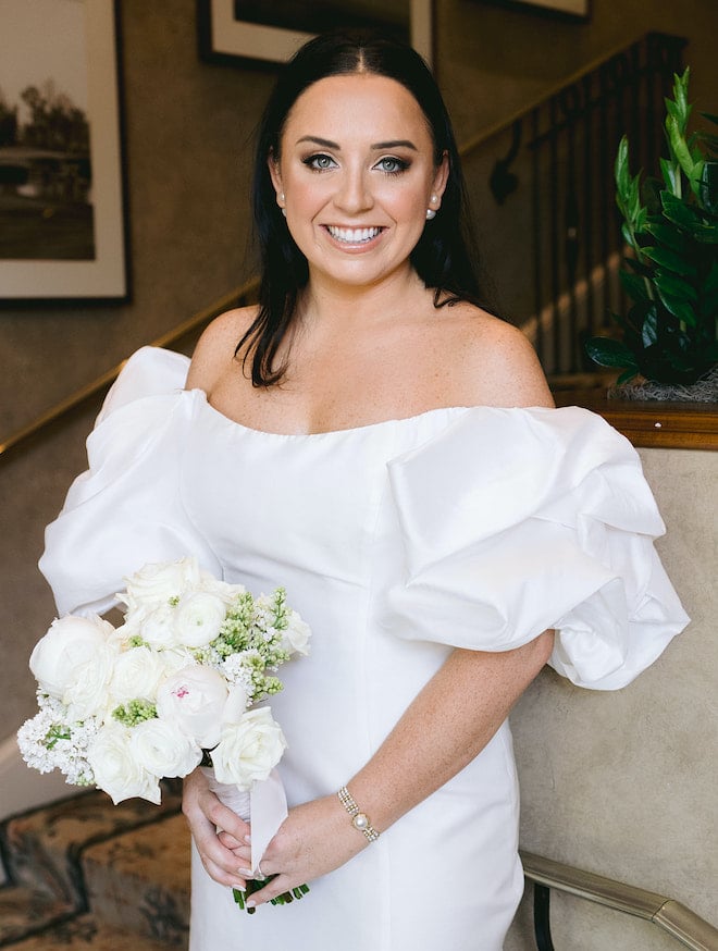The bride smiling with a white bouquet of flowers for her spring wedding.