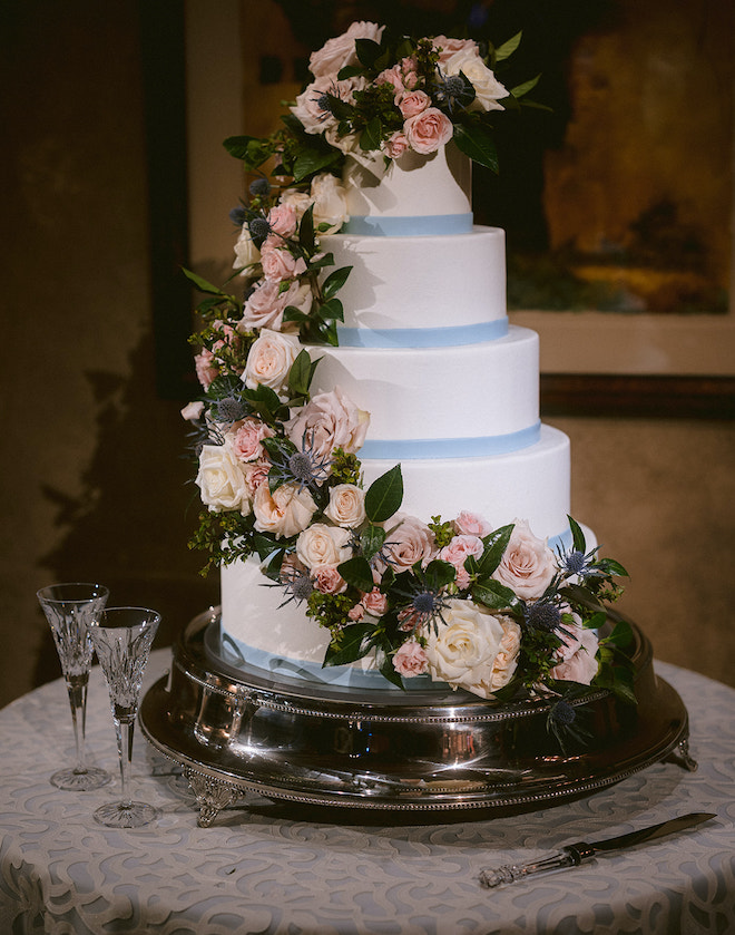 A five-tier wedding cake with light blue, pink and cream flowers for a spring wedding.