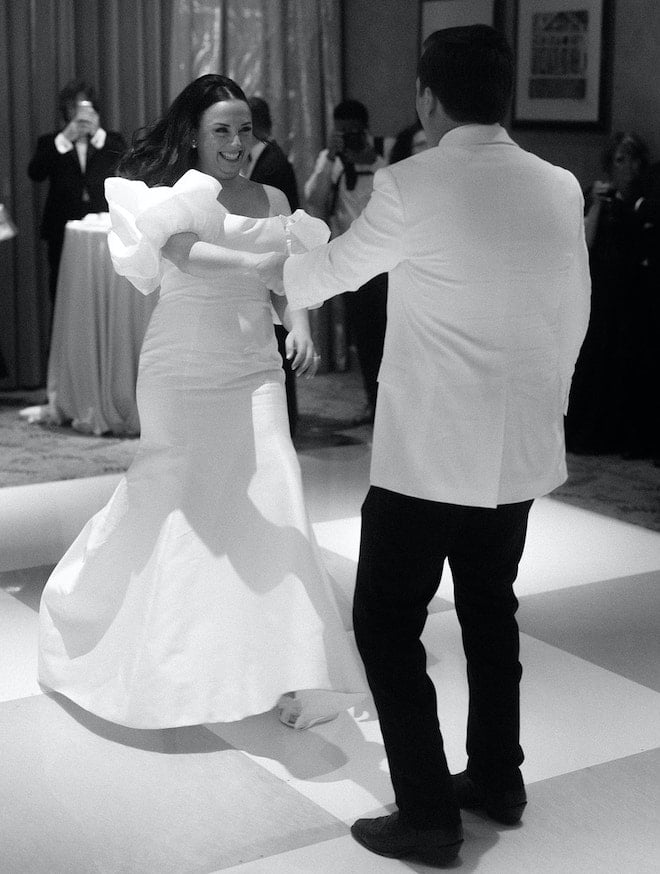 The bride and groom dancing on a checkered dance floor.