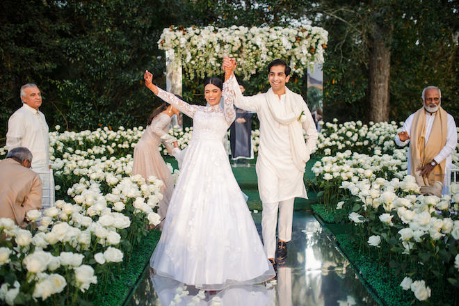 The bride and groom cheering as they walk back down the aisle after their opulent wedding ceremony.