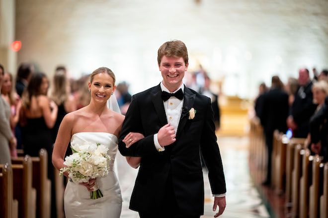 The bride and groom latching arms and smiling as they walked back down the aisle.