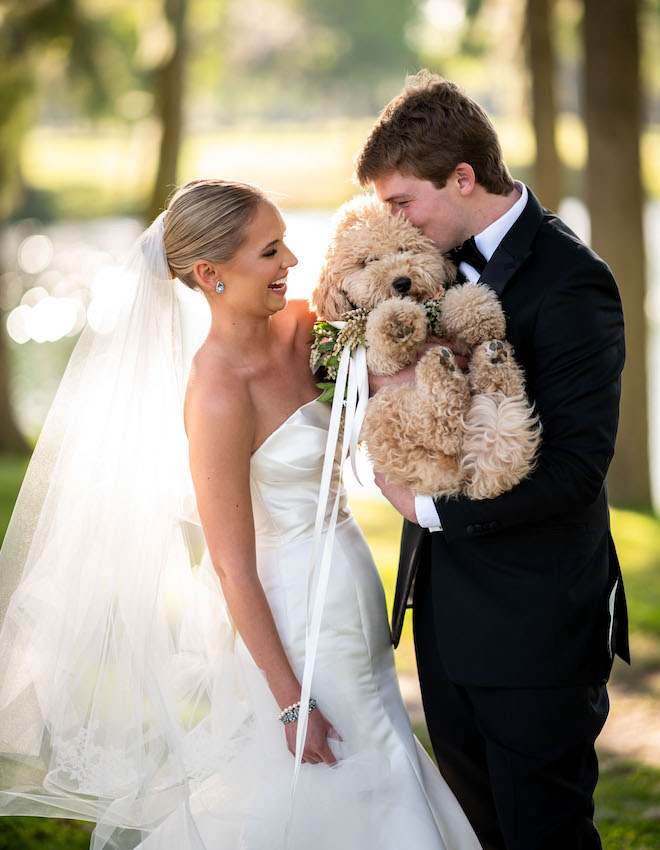 The bride and groom holding their puppy.