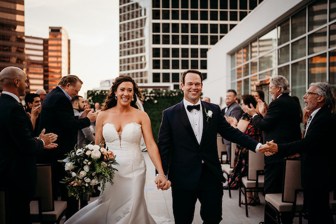 The bride and groom walking back down the aisle after their rooftop ceremony at the Westin Houston Medical Center.