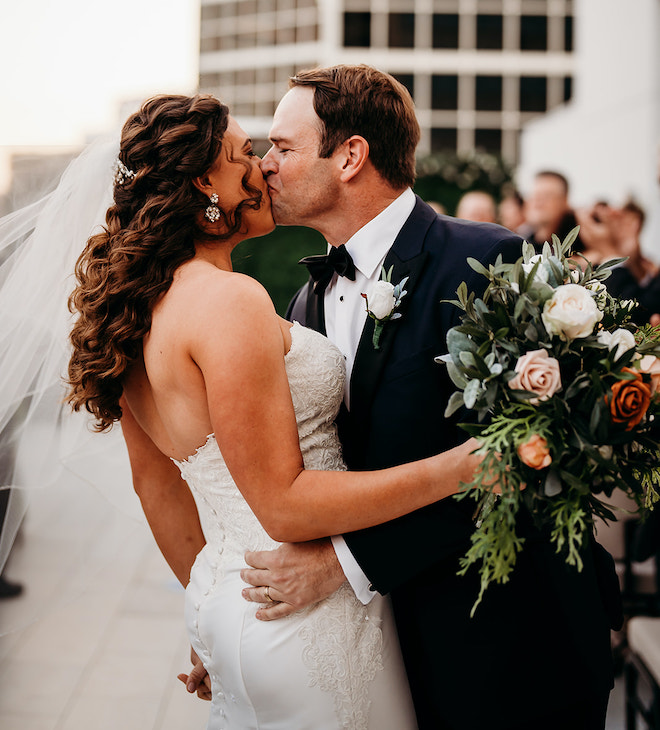 The bride and groom kissing down the aisle after their rooftop wedding ceremony.