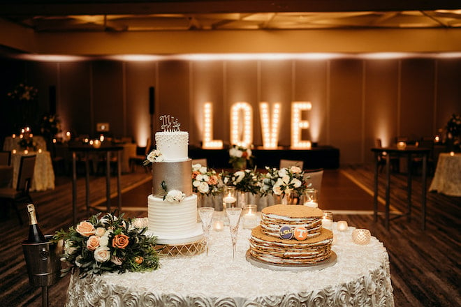 The bride and groom's cakes with lit uo "Love" marquee letters in the back.