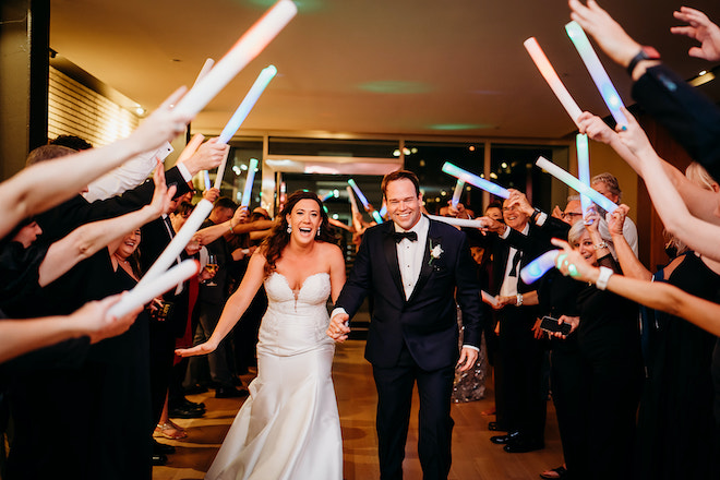 The bride and groom holding hands laughing during their send off.