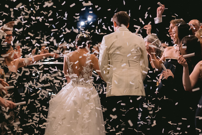 The bride and groom walking through white confetti for their sendoff. 