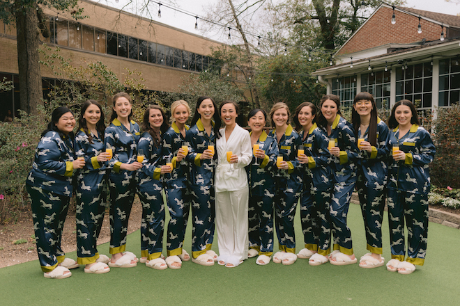 The bride in white pajamas smiling with her bridesmaids in blue and yellow pajamas with tigers printed on them. 