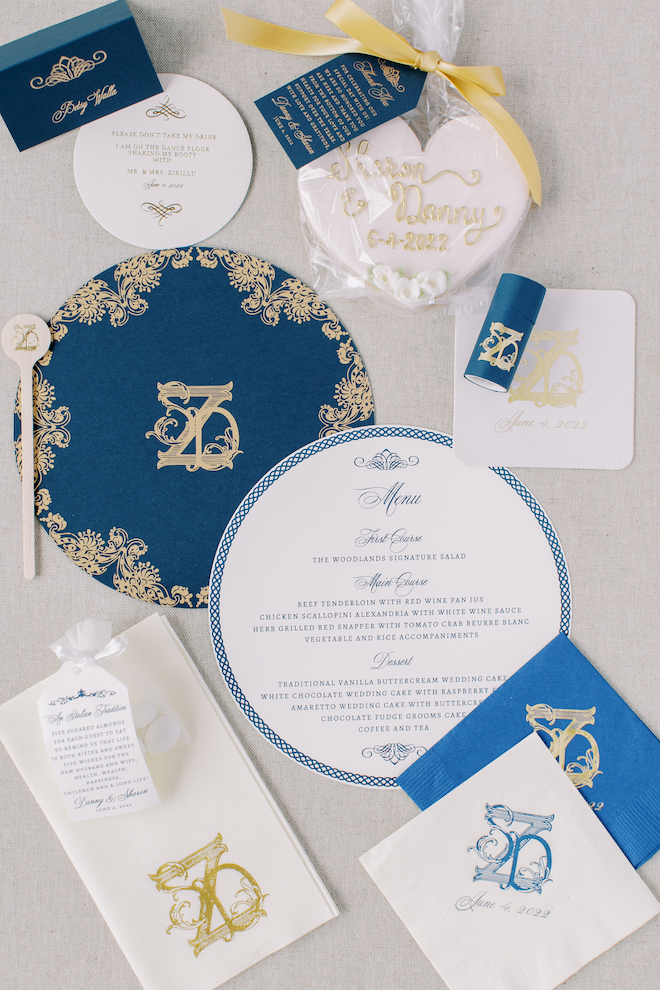 A white, navy and gold invitation suite including the menu, napkins and customized cookies that say "Sharon and Danny".
