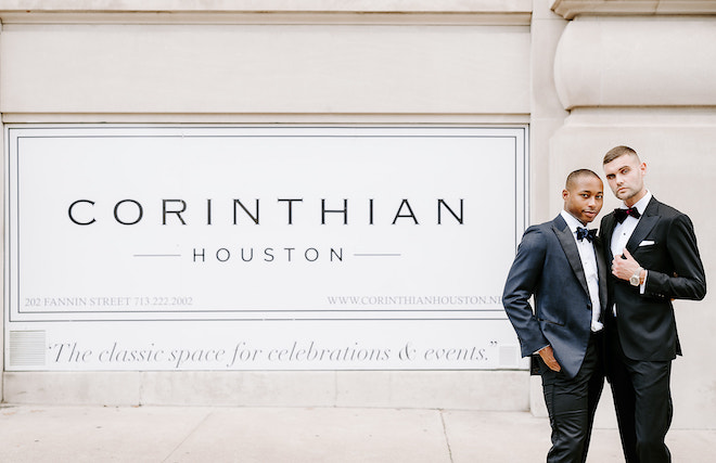 The two groom's stand beside the Corinthian Houston sign outside the wedding venue in Downtown Houston. 