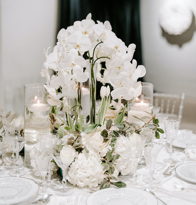 White orchids and candlelight decorate the reception tables at the wedding reception. 