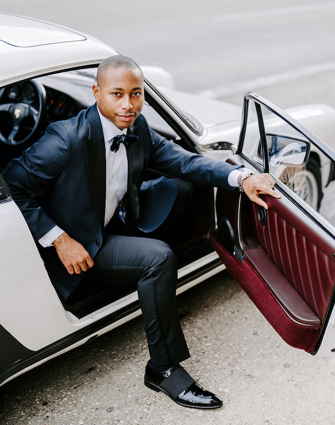 The groom steps out of the vintage white Porsche. 