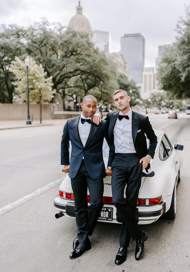 The two grooms pose in front of the vintage Porsche overlooking the Houston Skyline. 