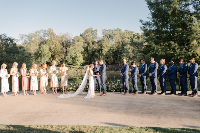 A bride and groom holding hands at their al fresco wedding ceremony overlooking the Colorado river.