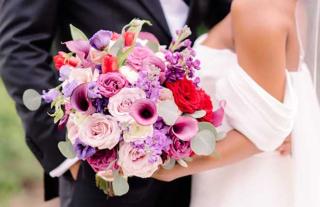 A bouquet with florals in shades of purple and red.