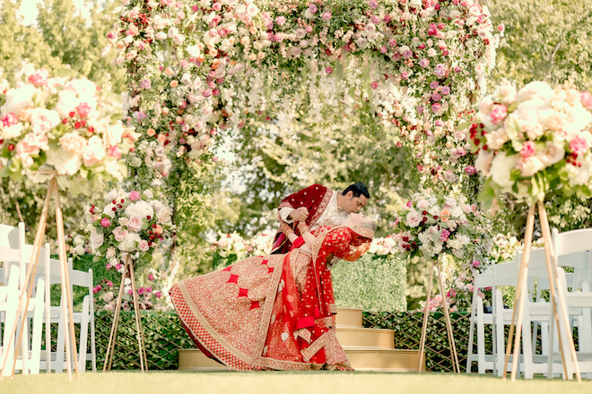 A bride and groom kissing under a floral filled Mandap at their wedding at Hyatt Regency Lost Pines Resort and Spa.