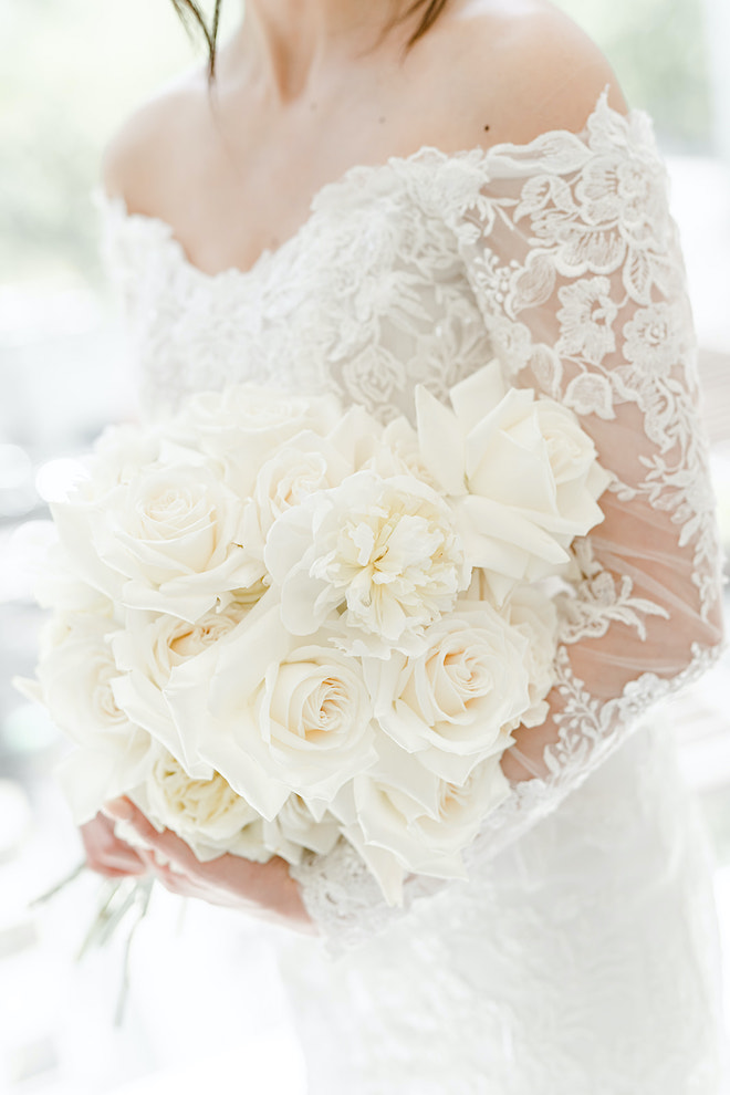 The bride holding an all-white bouquet for her timeless champagne colored wedding.