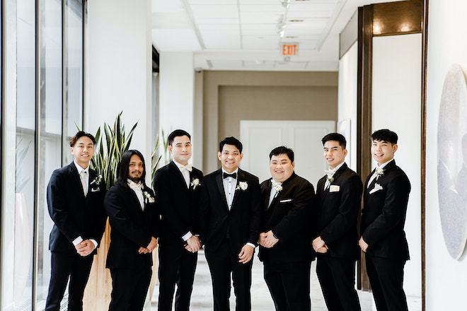 The groom and his groomsmen smiling before the timeless champagne colored wedding.
