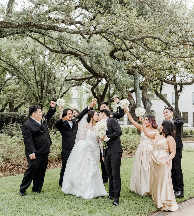 The bride and groom kissing as the wedding party cheers.