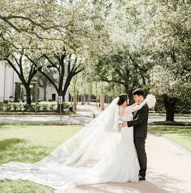 The bride and groom smiling at each other at their timeless champagne colored wedding.