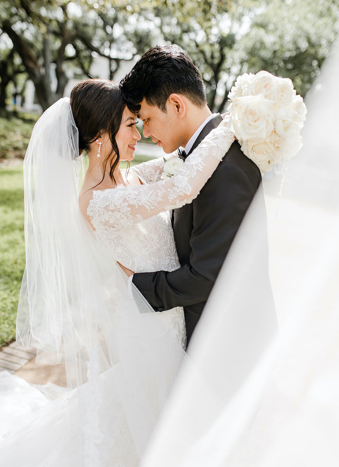 The bride and groom smiling at eachother and hugging at their timeless champagne colored wedding,