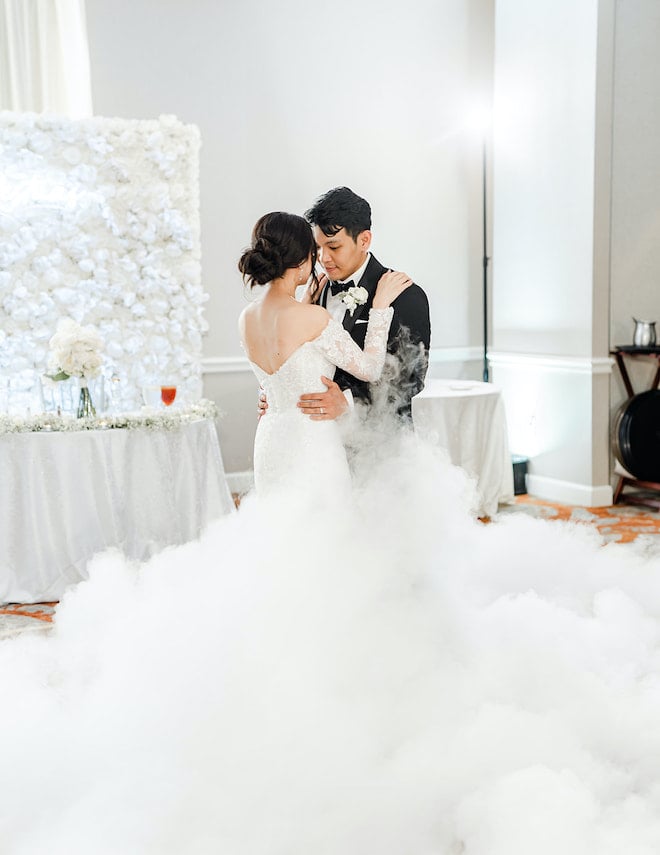 The bride and groom sharing their first dance as white fog fills the floor.