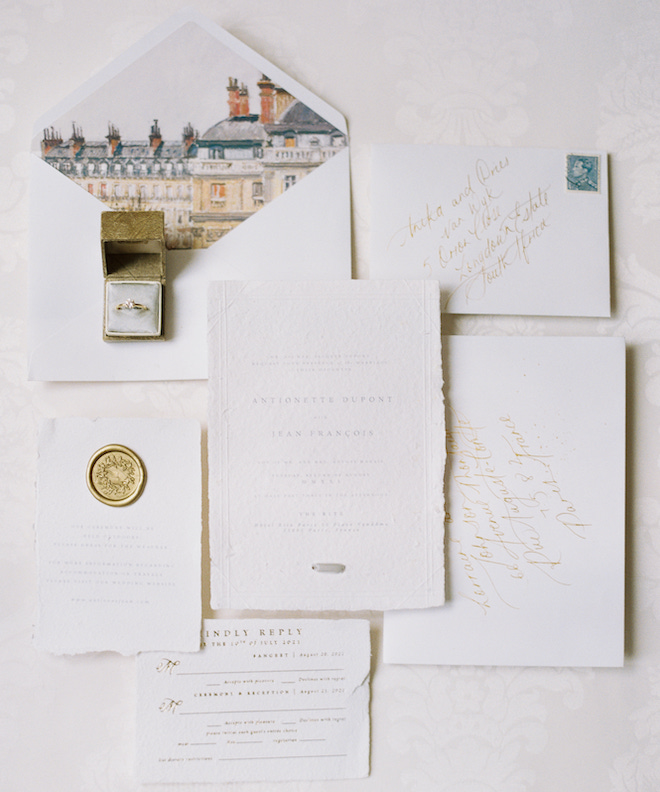 White and gold invitation suite with a print of a Parisian building on the inside of the envelope.