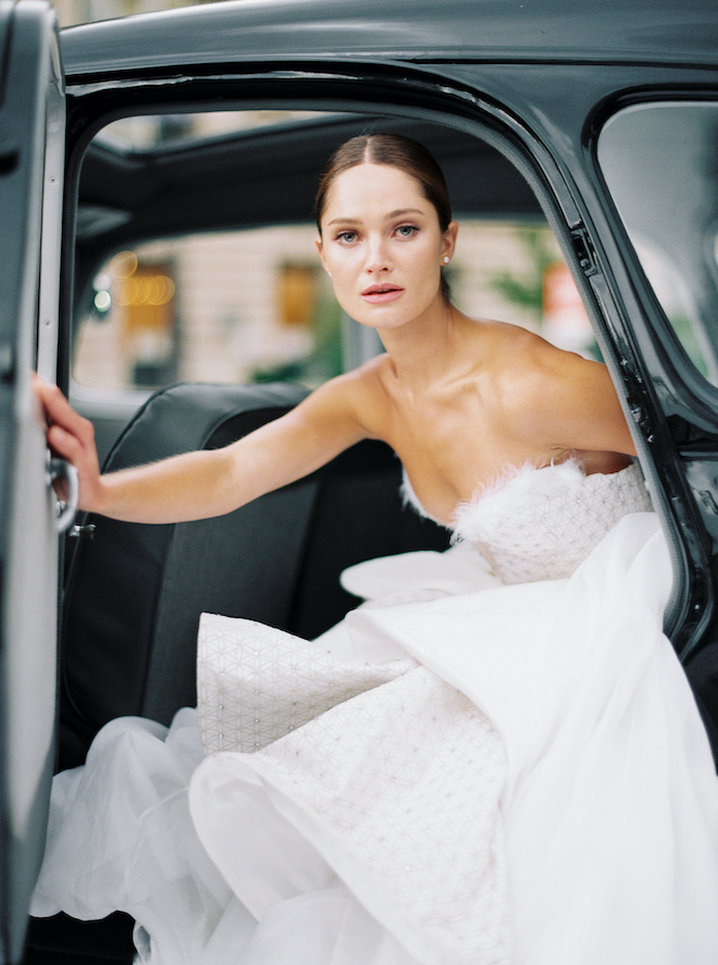 The bride opening the car door, posing for the Parisian love story by Sean Thomas Photography.