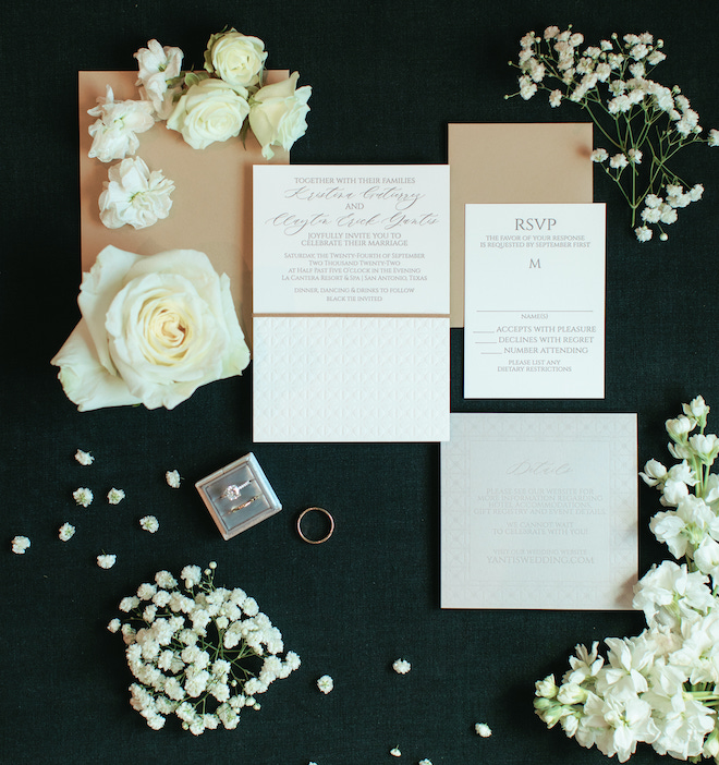The oyster-toned invitation suite surrounded by roses and baby's breath.