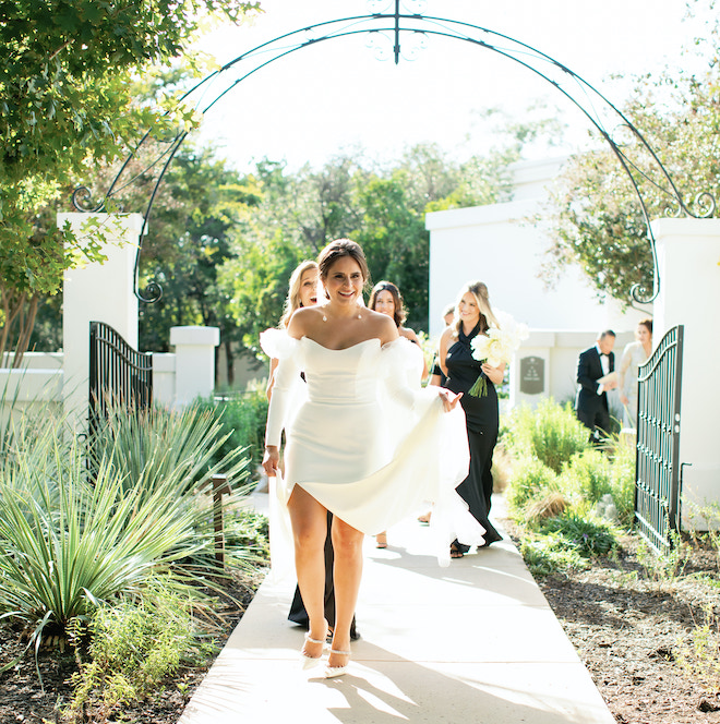 The bride holding her dress as she walks with her bridesmaids to the wedding venue in the San Antonio hill country.