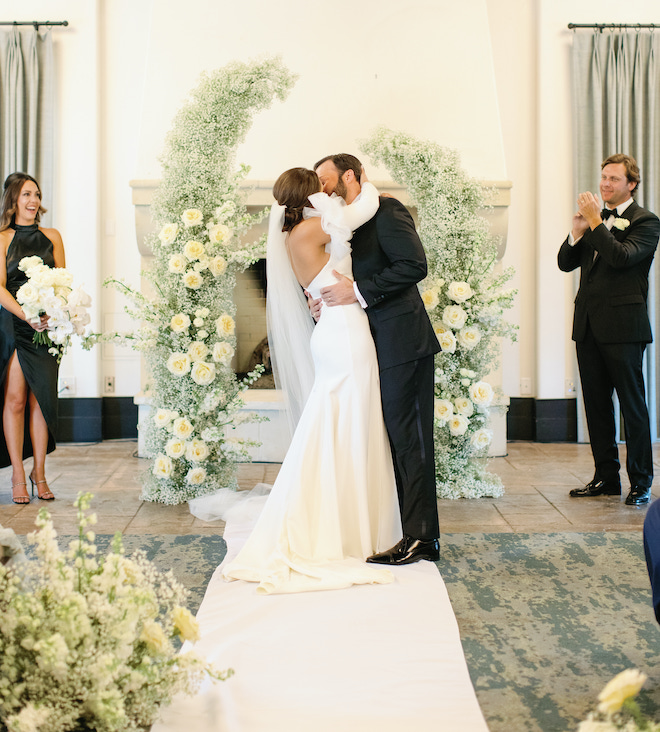 The bride and groom kissing at the altar during their wedding ceremony in the San Antonio hill country.