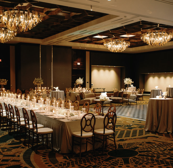 The ballroom of the wedding reception in the San Antonio hill country, decorating with a long reception table with candlelight, couches and a dancefloor.