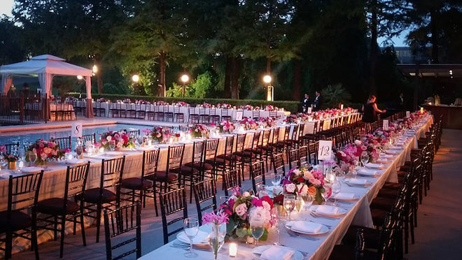 Long dinner tables set up outside the pool of Omni Houston Hotel, a rehearsal dinner venue.