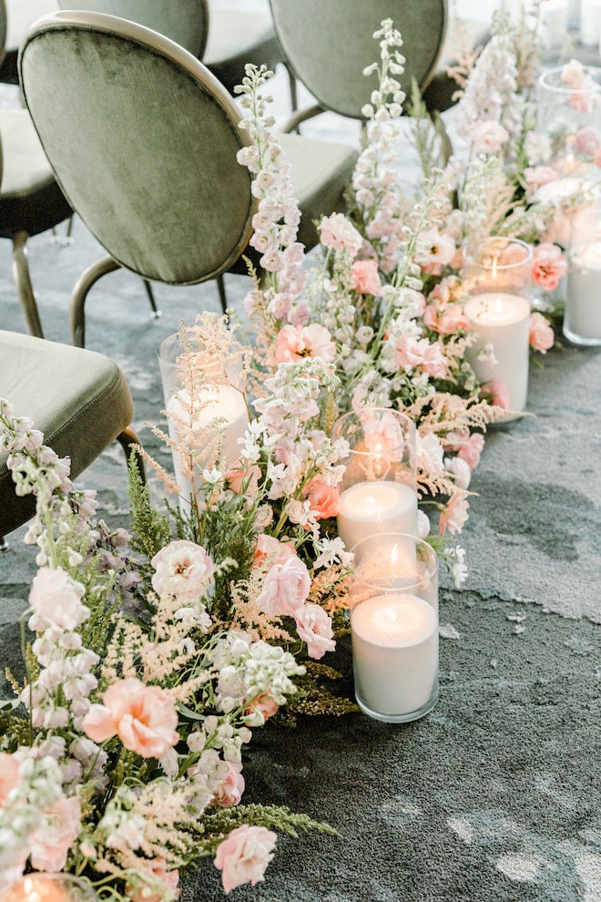 Delicate florals and candlelight lining the aisle of the ceremony space.