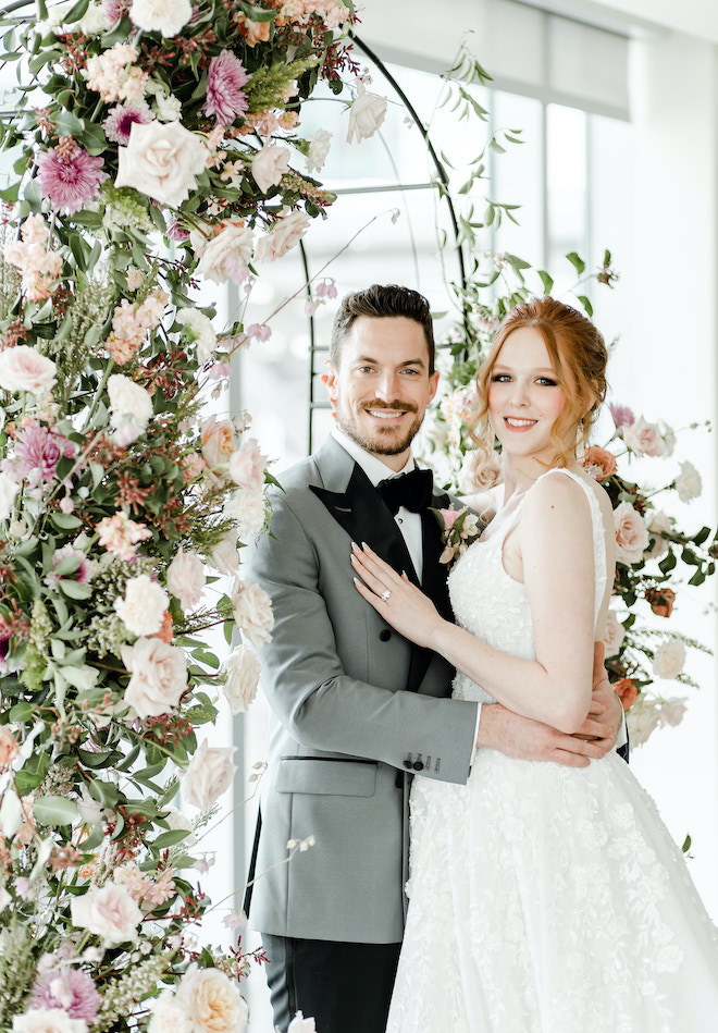 The bride and groom smiling under the floral filled altar.