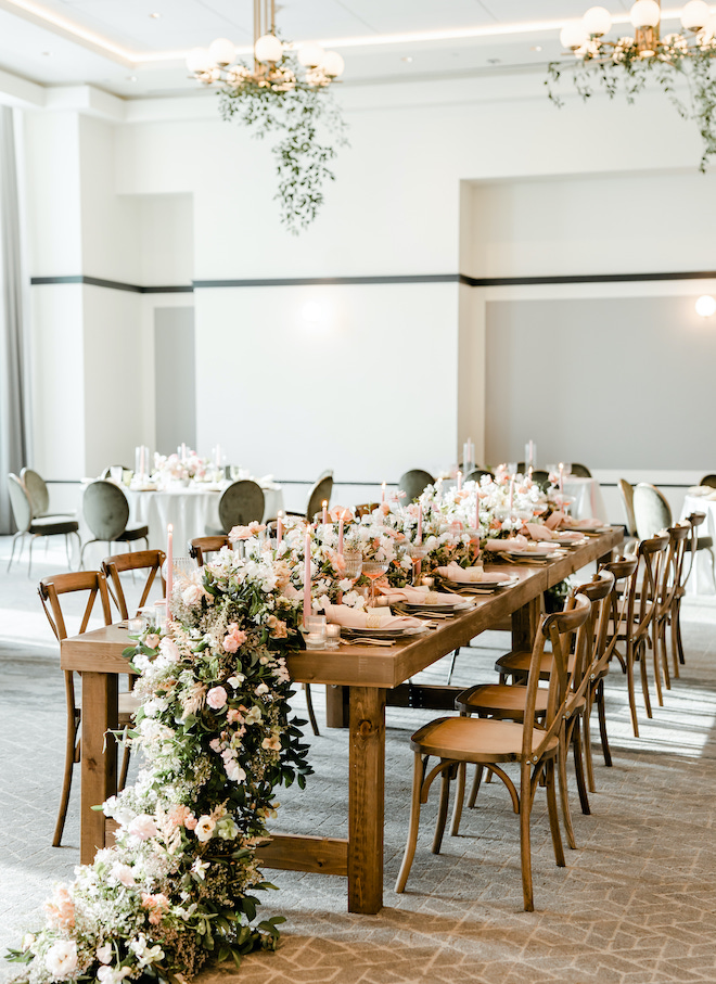 Greenery and florals decorating the head table at the reception of the light & airy wedding editorial.