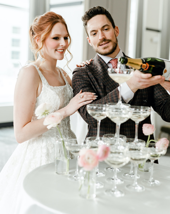 The bride and groom pouring champagne into a tower of glasses.