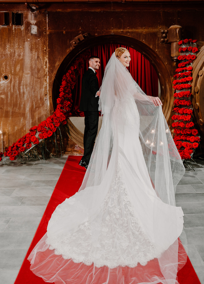 The groom leading the bride into the Vault, surrounded by red roses.