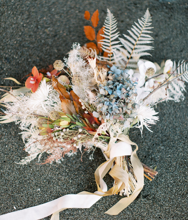 A bouquet of orange, blue and white florals.