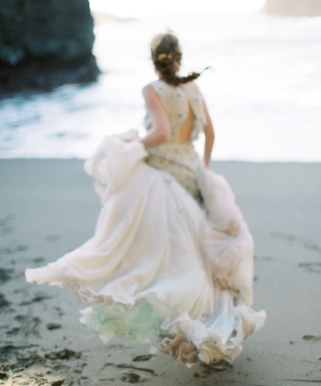 The bride running in the sand toward the water of the Oregon Coast.